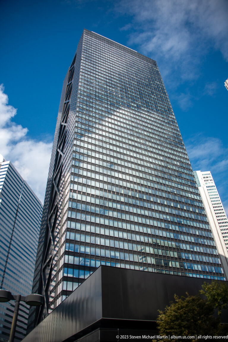 Low-angle view of a large glass office tower with a gridded curtain wall in Shinjuku.