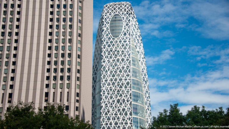 Close view of the Mode Gakuen Cocoon Tower’s rounded glass façade and white diagonal lattice.