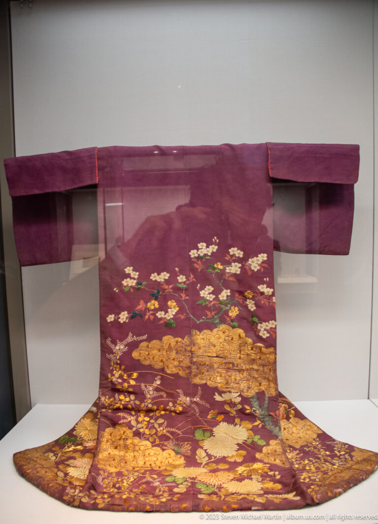 Purple formal robe with broad sleeves and dense gold floral and landscape embroidery.