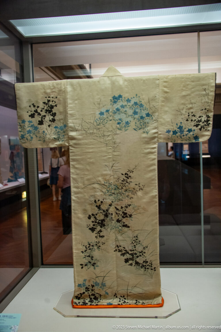 Light-colored robe with branching blue and black motifs across the sleeves and lower body.