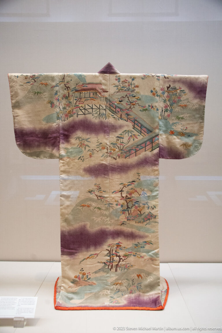 Light robe with bridges, pavilions, figures, trees, and broad purple cloud bands.