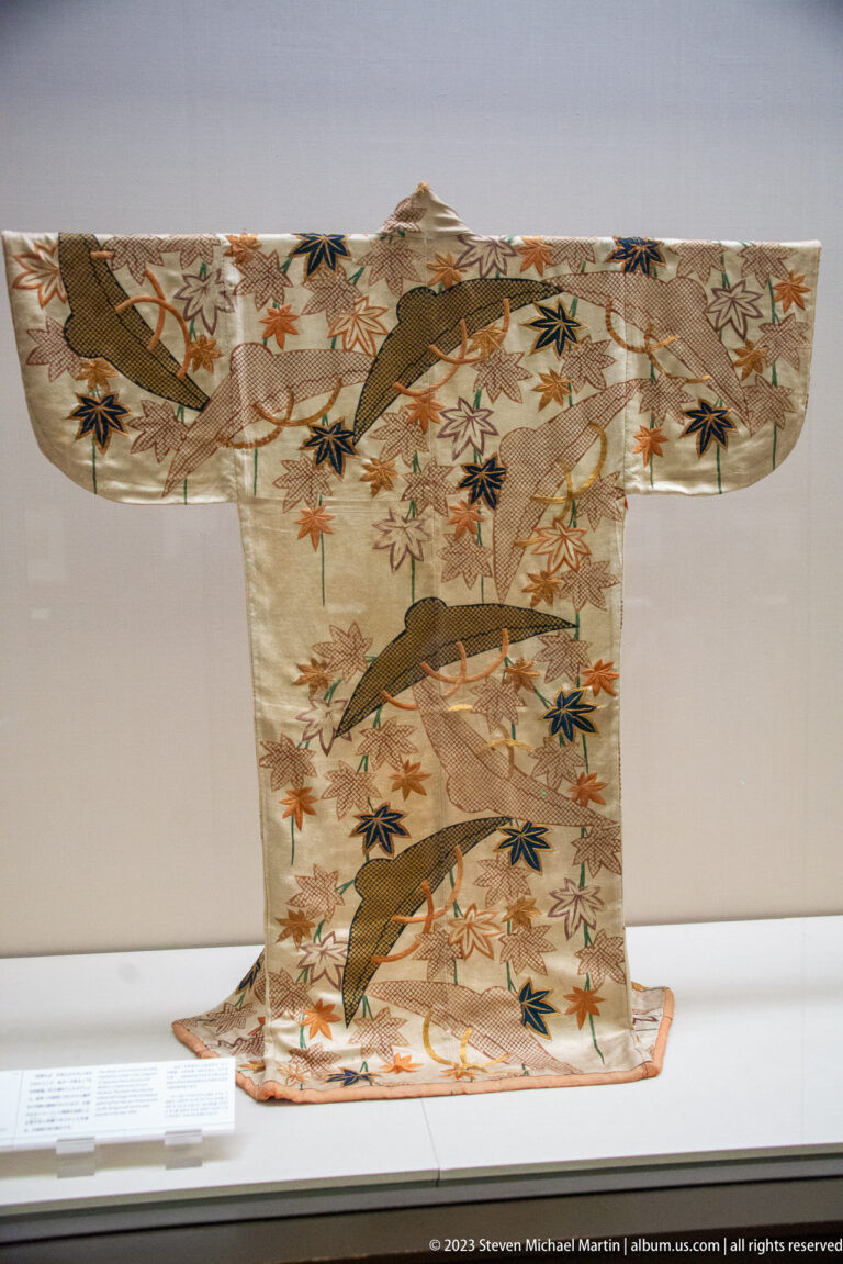 Light kimono with branching trees, multicolored maple leaves, and small birds.