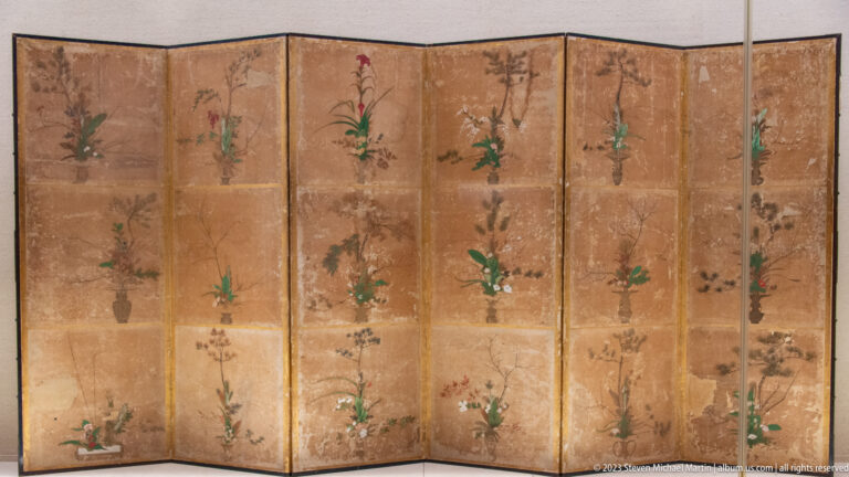 Multi-panel folding screen with repeated potted flowering plants on a gold-brown ground.
