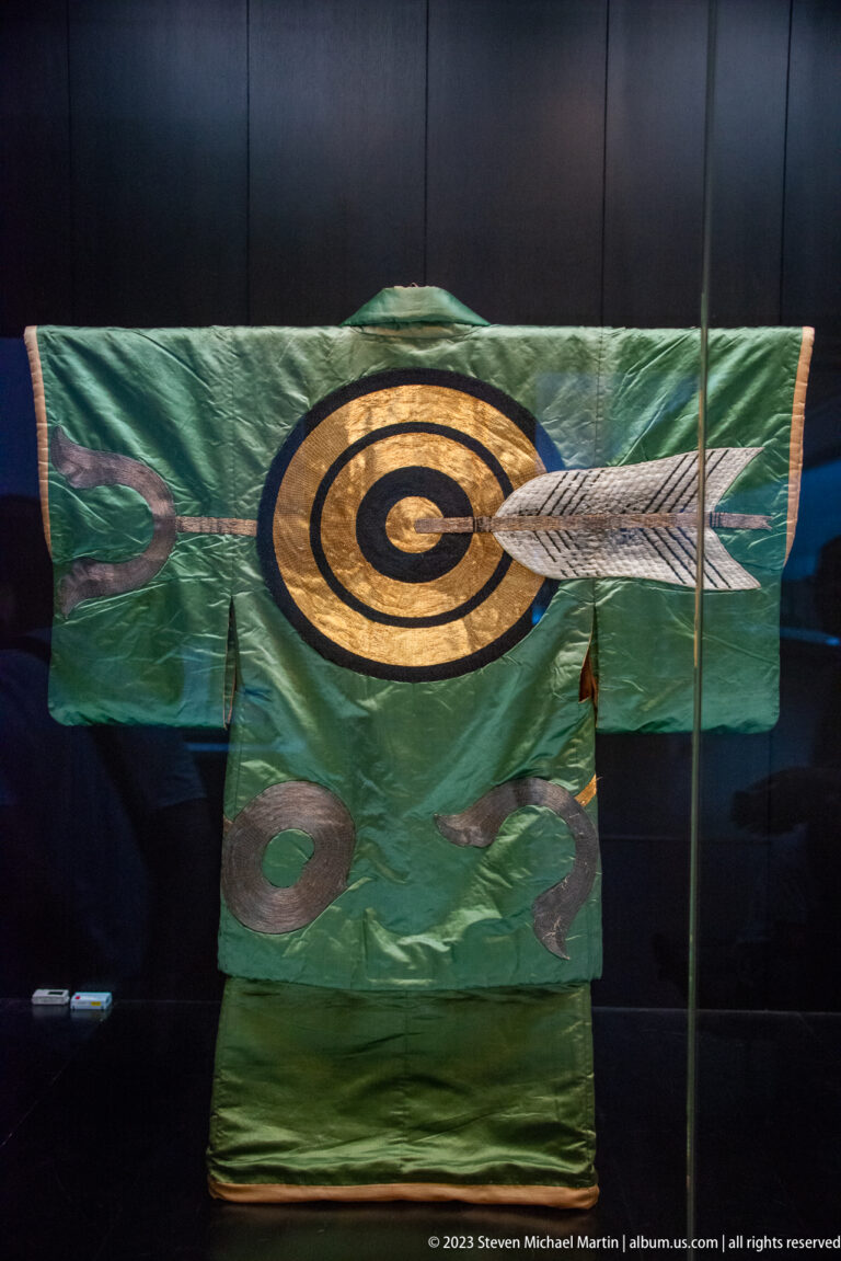Green robe decorated with a large circular archery target pierced by an arrow.