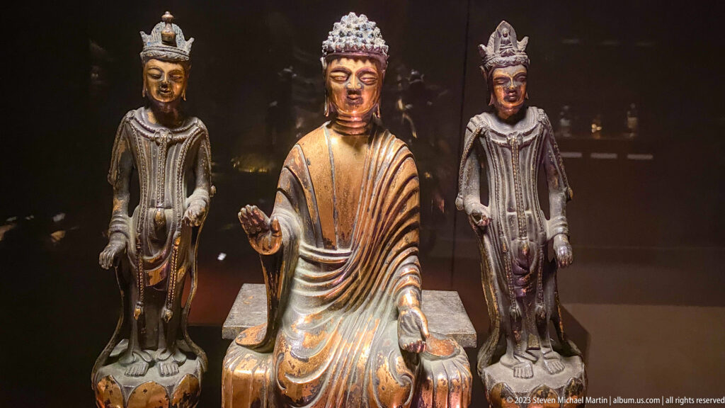 Seated Buddha centered between two standing attendants with traces of gilding.
