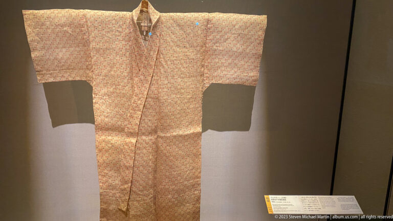 Light kimono covered with a dense repeating pattern of small red and blue motifs.