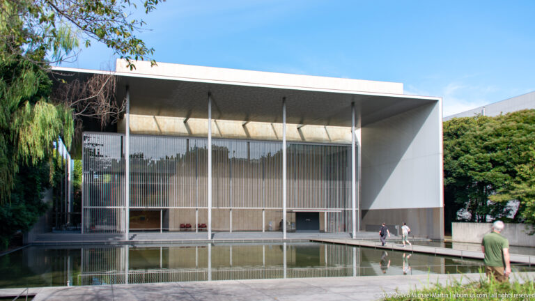 Modern Gallery of Horyuji Treasures with broad roof, vertical screen, reflecting pool, and visitors near the entrance.