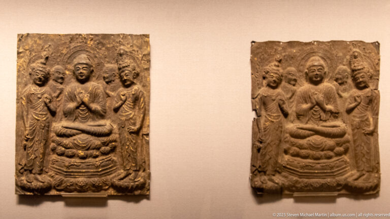 Two carved Buddhist plaques, each with a seated Buddha on a lotus throne and flanking attendants.