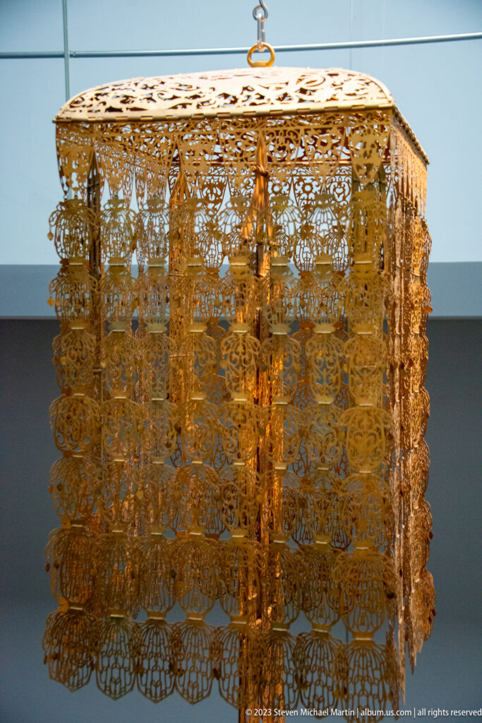 Square gilt-bronze canopy of the Kanjō-ban with openwork panels and suspended pendants.