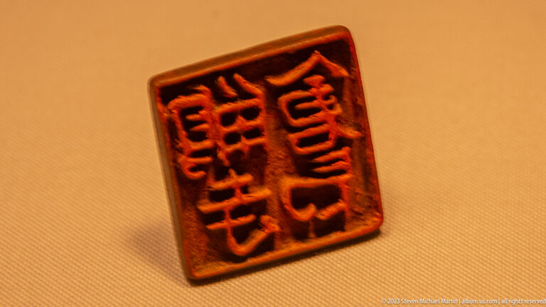 Square seal with red-highlighted carved Chinese characters on a dark face.