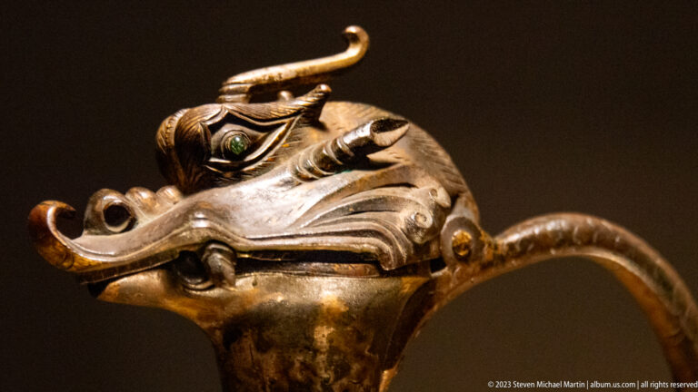 Close-up of the Dragon-Headed Ewer’s gilded dragon spout with curling horns and pale-green glass eye.