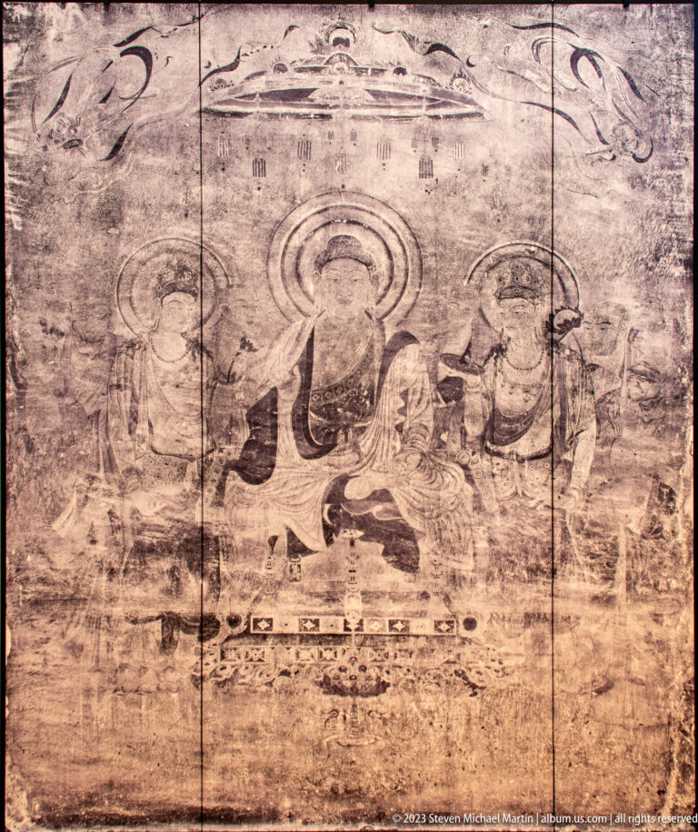 Faded Buddhist mural with a central haloed figure, attendants, and extensive surface loss.