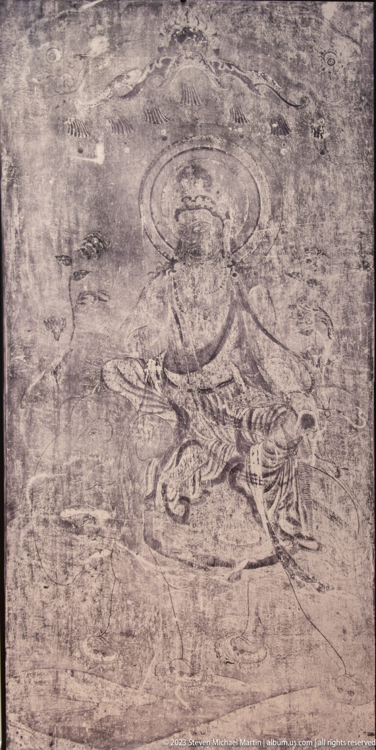 Faded seated haloed figure holding an object on a heavily abraded mural.