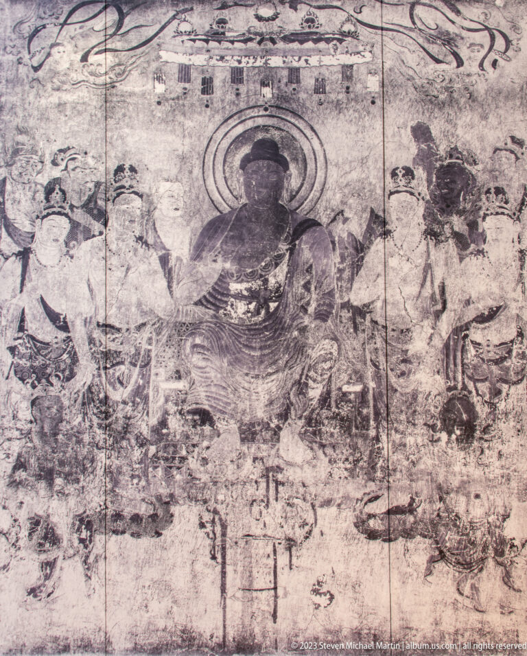 Faded mural with a large seated Buddha surrounded by many smaller attendants and sacred figures.