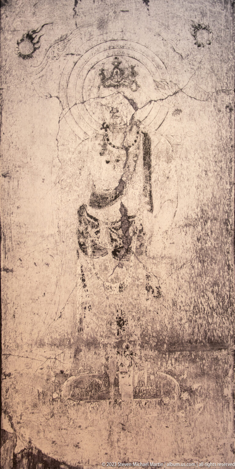 Small faded seated haloed figure turned slightly to one side on a damaged mural.