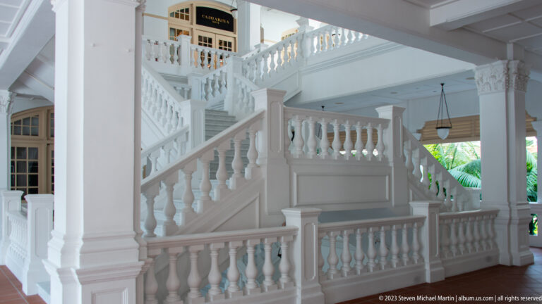 Overlapping white stair flights and balustraded landings in a tall colonial-style interior.