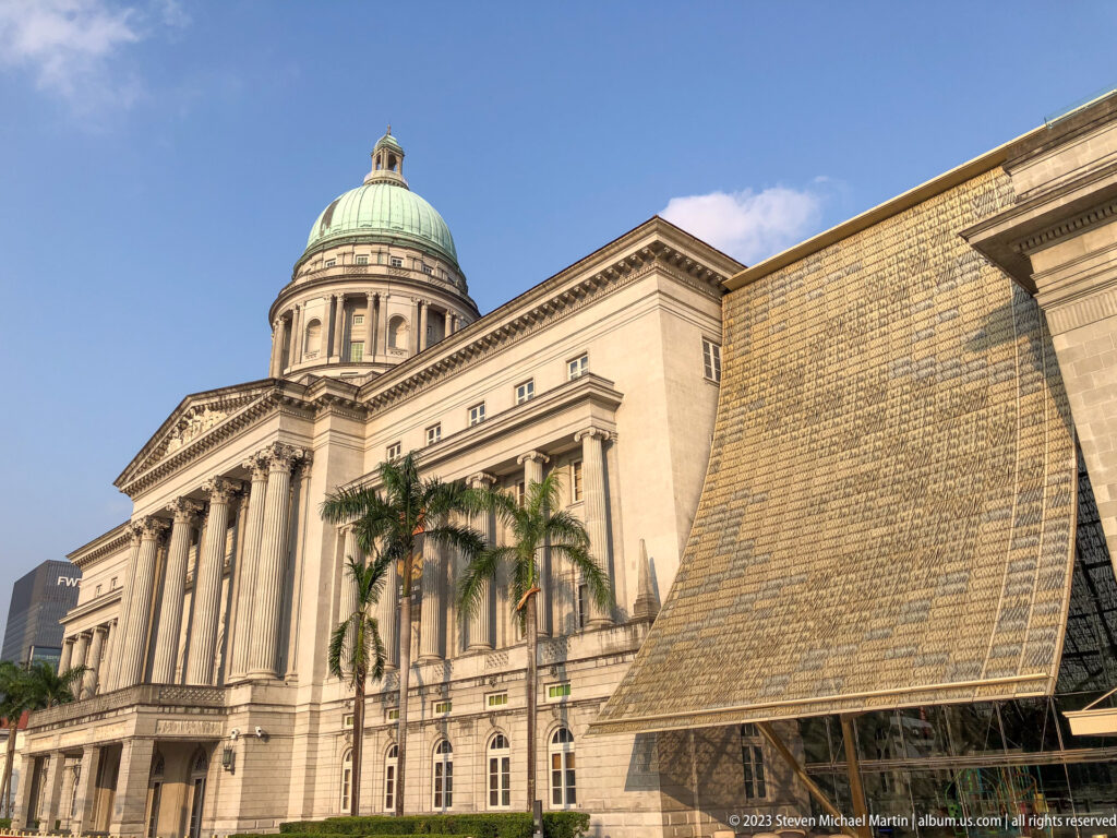Domed neoclassical former Supreme Court building behind a large text-covered installation wall.