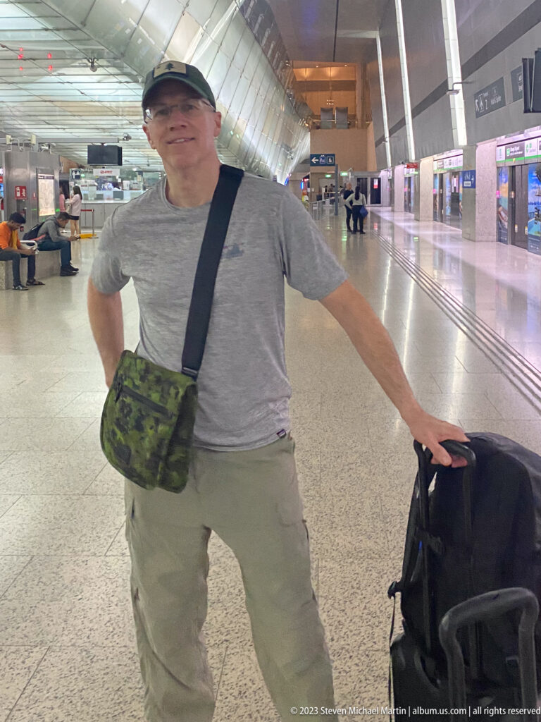 Male traveler standing with luggage inside a bright Singapore MRT station.