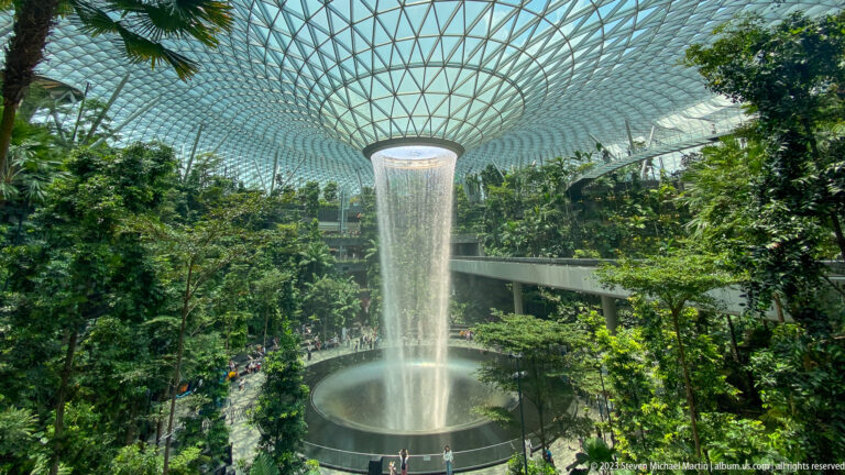 Wide elevated view of the Rain Vortex beneath Jewel Changi Airport’s glass dome.