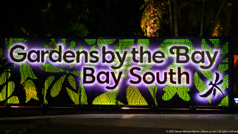 Illuminated Gardens by the Bay Bay South sign with green leaf patterns against a dark nighttime garden.