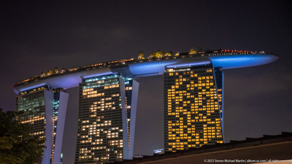 Marina Bay Sands illuminated at night with three towers supporting its long rooftop deck.