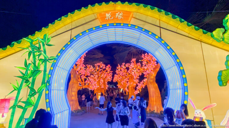 Blue-lit circular gateway with bamboo and rabbit decorations opening onto blossom trees.