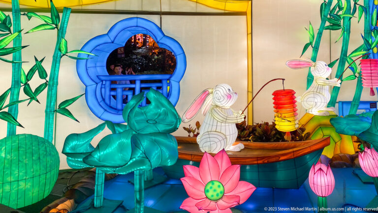 Lantern tableau with white rabbits, lotus flowers, bamboo, and a boat form.
