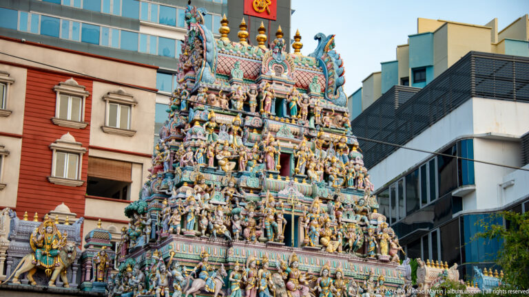 Close view of Sri Veeramakaliamman Temple gopuram covered with brightly painted Hindu figures and shrine forms.