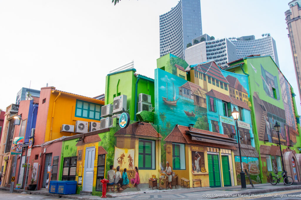 Colorful Little India building covered with a mural of shophouses, windows, and street scenes.