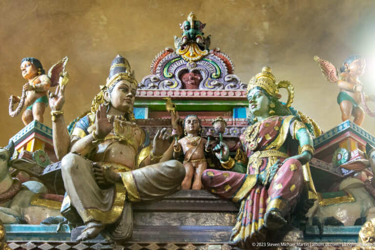 Seated divine couple with a child beneath an ornate canopy and smaller attendant figures.