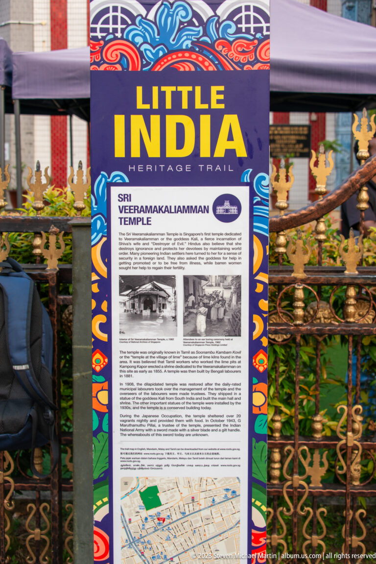Little India Heritage Trail sign about Sri Veeramakaliamman Temple beside an ornate metal fence.