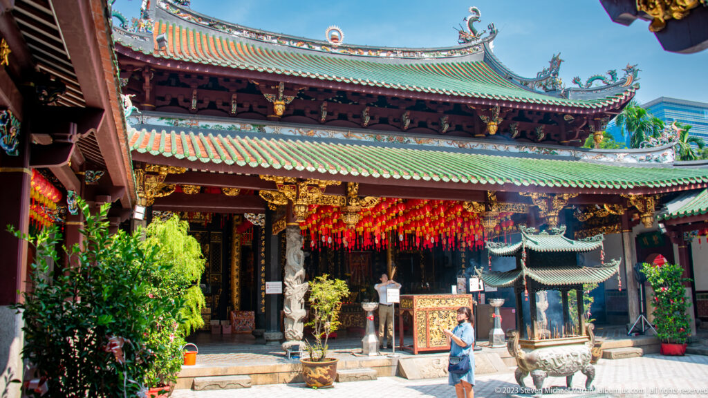 Thian Hock Keng hall with green tiled roofs, red columns, hanging lanterns, incense burner, and visitors.