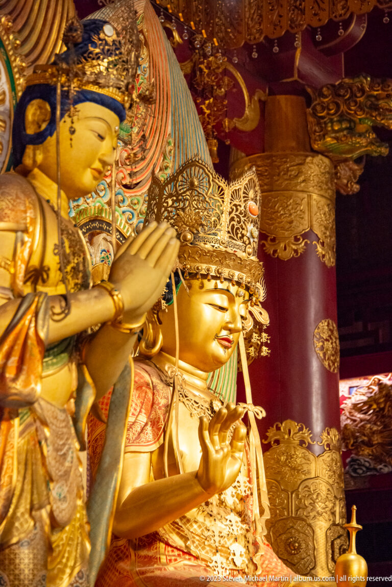 Close gilded bodhisattva figures with elaborate crowns, jewelry, and raised devotional gestures.