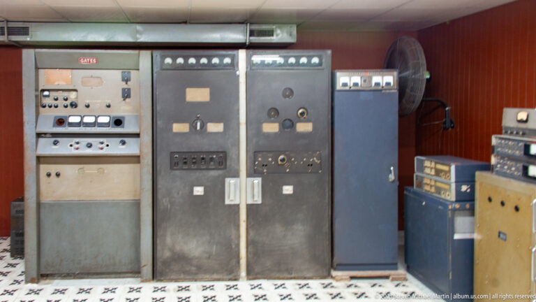 Tall gray control cabinets with gauges, switches, access doors, and adjacent radio equipment in the bunker.