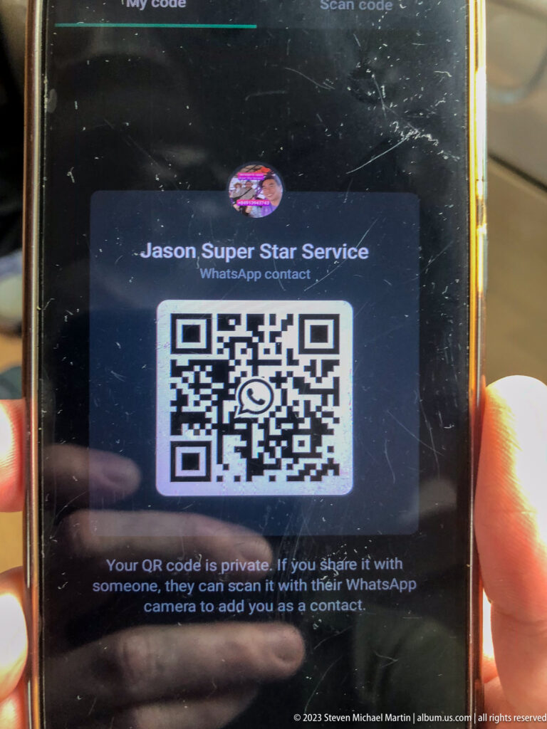 Handheld smartphone displaying a WhatsApp contact QR code for Jason Super Star Service.