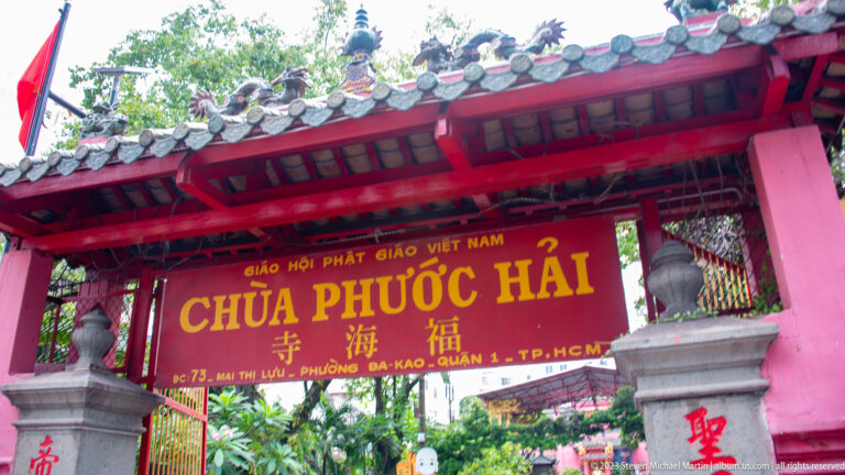 Red temple gateway with tiled roof and a large Chùa Phước Hải sign in Vietnamese and Chinese.