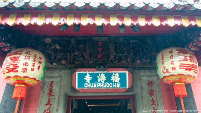 Temple doorway with two large inscribed lanterns beneath the blue Chùa Phước Hải sign.