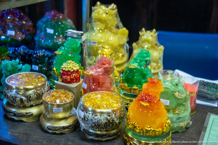 Colorful resin guardian figurines and small gold-filled bowls arranged on a display table.