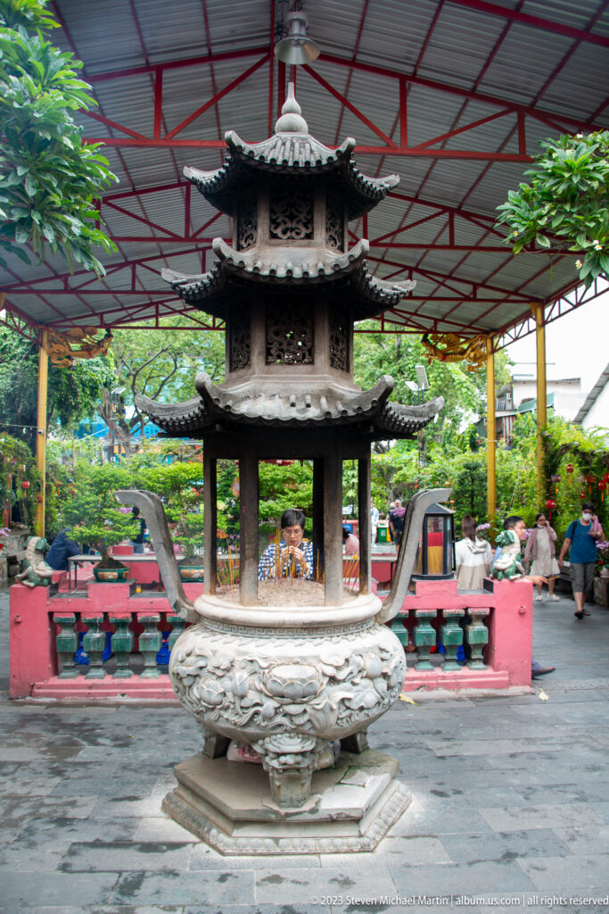 Large gray stone incense burner shaped like a tiered pagoda in the temple courtyard.