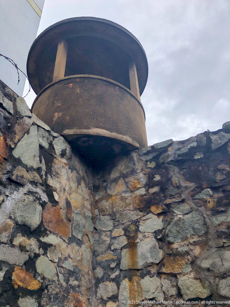 Low-angle view of a circular guard platform above a rough stone wall.