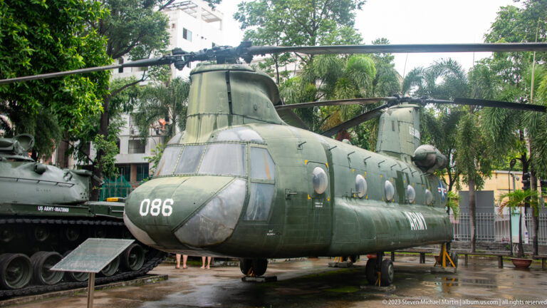 Olive-drab CH-47 Chinook helicopter with tandem rotors displayed outdoors.