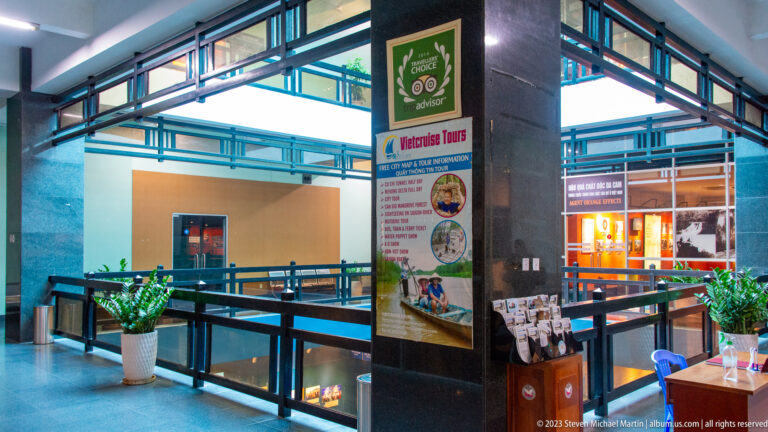 Upper-level museum balcony with railings, plants, and a visitor-information stand.