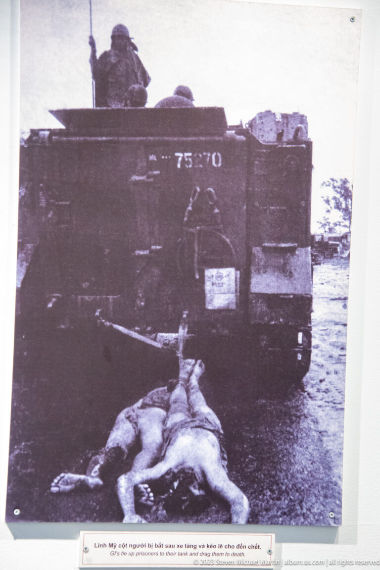 Black-and-white photograph of a body beside a military vehicle.