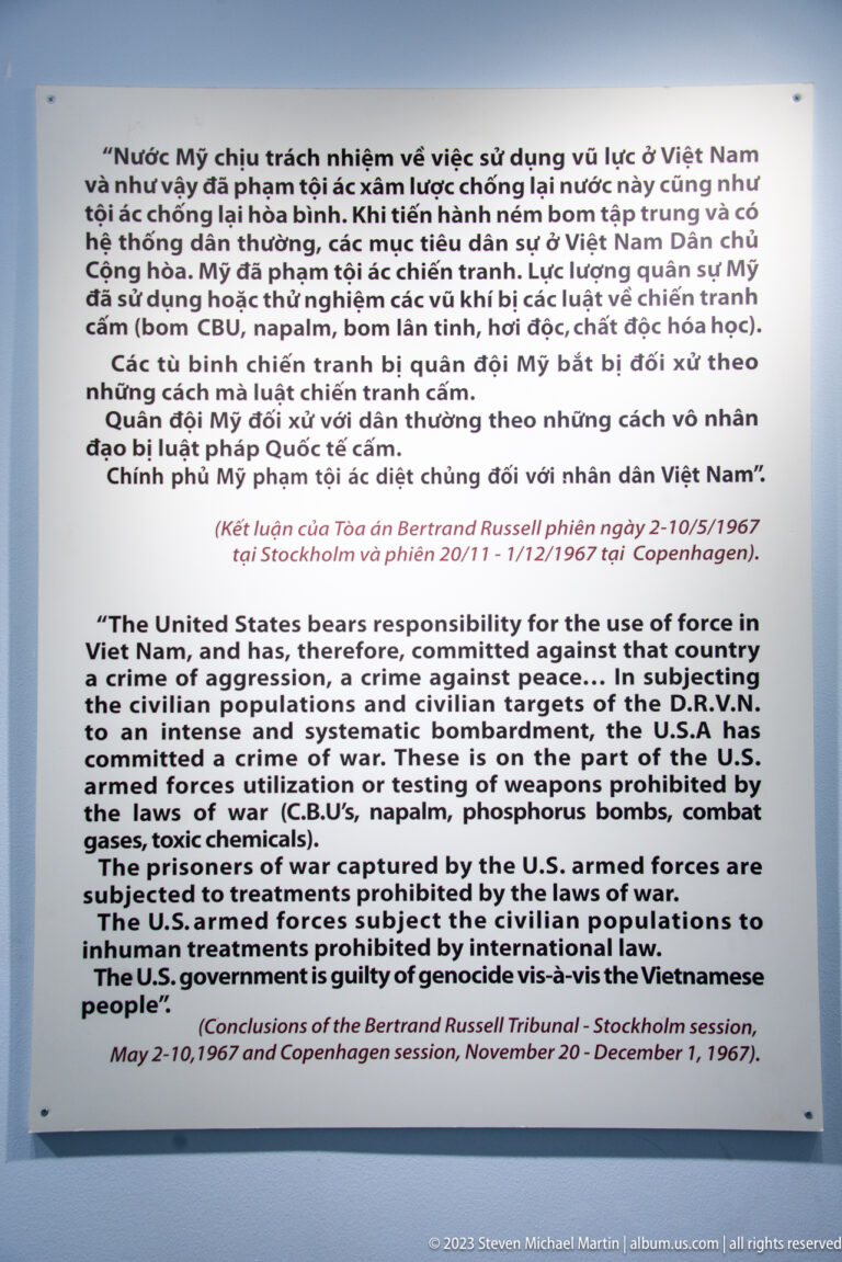 White bilingual museum panel with text about war crimes and the Russell Tribunal.