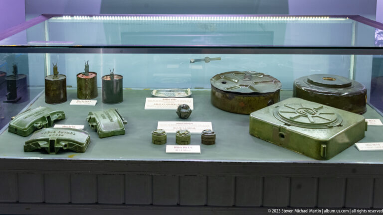 Glass case containing land mines, fuzes, and small explosive devices.