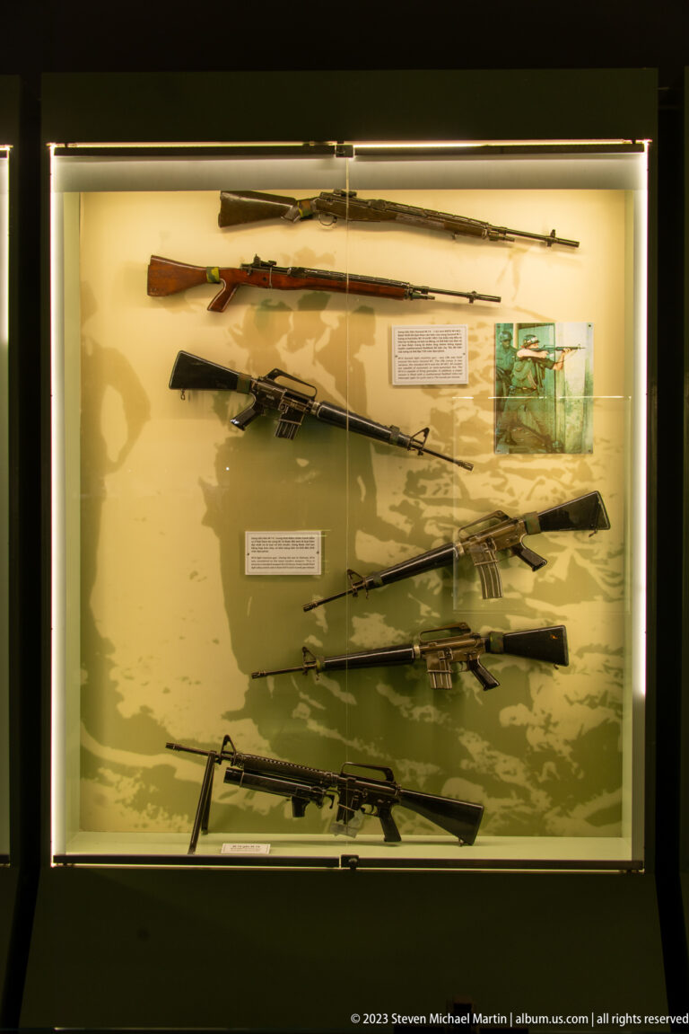 Glass case displaying rifles, carbines, and machine guns.