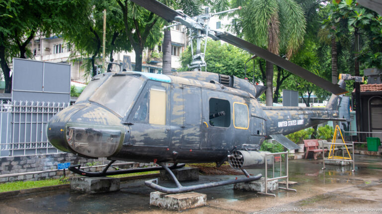 Weathered Bell UH-1 Huey helicopter displayed outdoors with rotor extended.