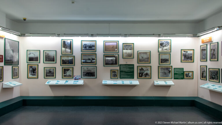 Bright white gallery with framed photographs, labels, and display cases.