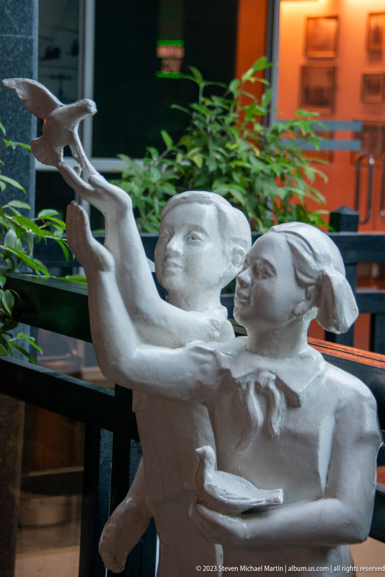 Two sculpted women raising a bird above their heads.