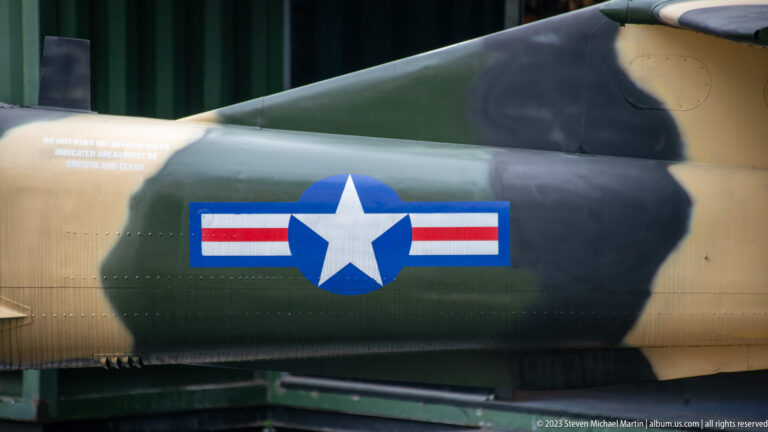 U.S. star-and-bar insignia on a camouflaged riveted aircraft fuselage.